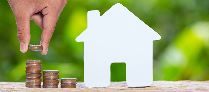 Stacking coins next to a paper house